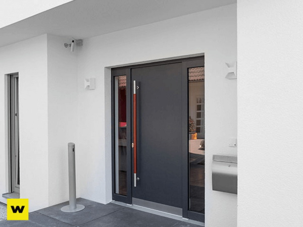 Moderne Haustür aus Aluminium mit Seitenteil an einem weißen Einfamilienhaus-Eingang.